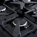 Close-up of a brass burner on the FORNO Antico 36-Inch Gas Range in black, showing precision flame ports, durable cast iron grate, and sleek black stainless steel surrounding the burner.