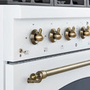 Close-up of the stainless steel control knobs on the FORNO Antico 36-Inch Gas Range in white, featuring polished brass bezels and precision temperature markings for professional-grade cooking control.