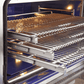 Interior view of FORNO Capriasca 36-Inch Gas Range featuring blue enamel cavity, convection fan, and three stainless steel telescopic oven racks.